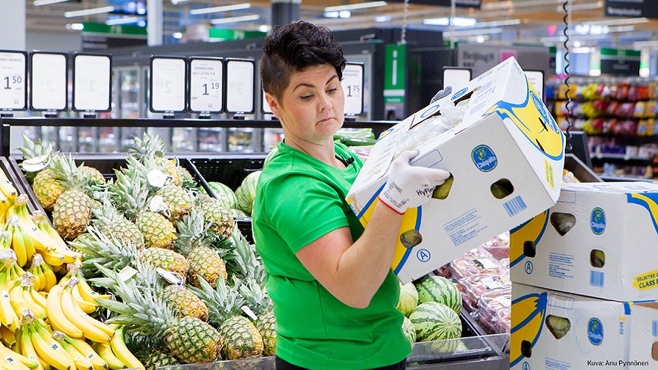 En person lyfter en låda med bananer.