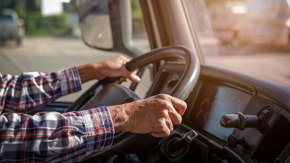 Rekka-auton kuljettajan kädet ratissa.