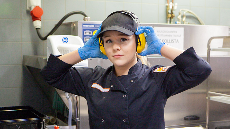 Ung arbetare med hörselskydd i öronen. Bild: : Anu Pynnönen.